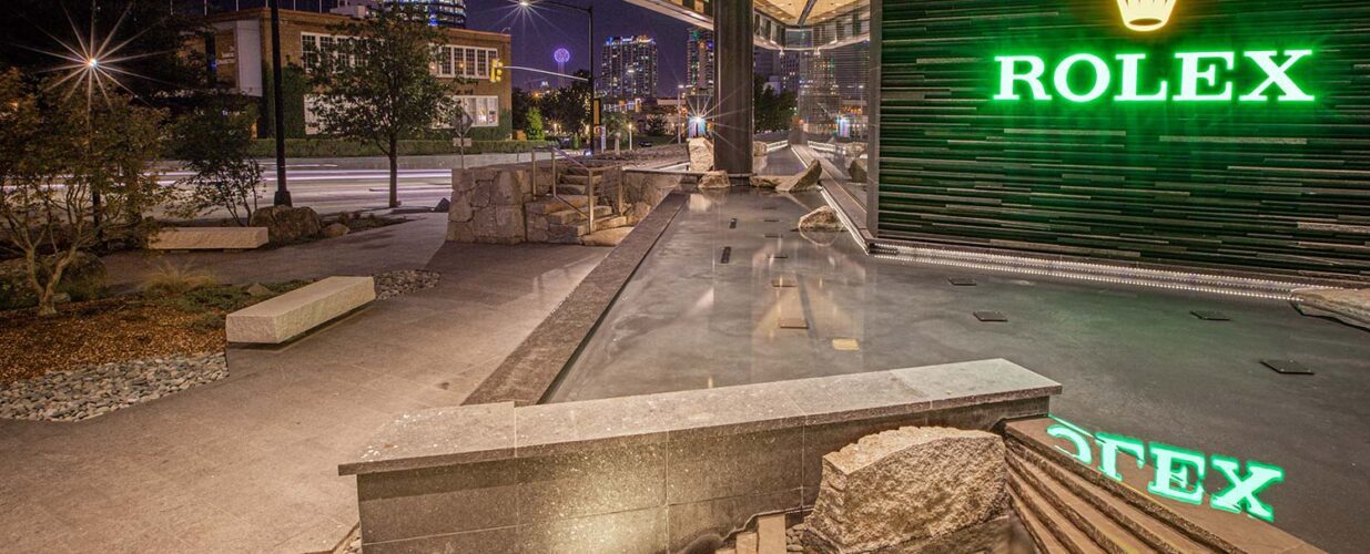 Rolex Plaza outdoor water feature with view of Dallas skyline at night